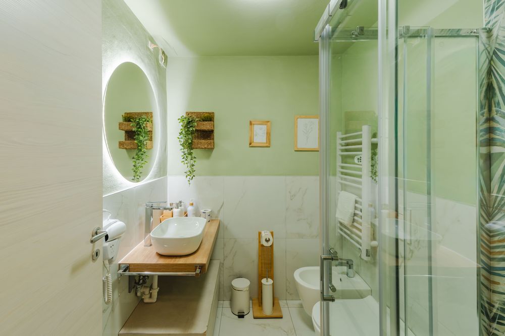 Bagno con specchio rotondo illuminato e box doccia