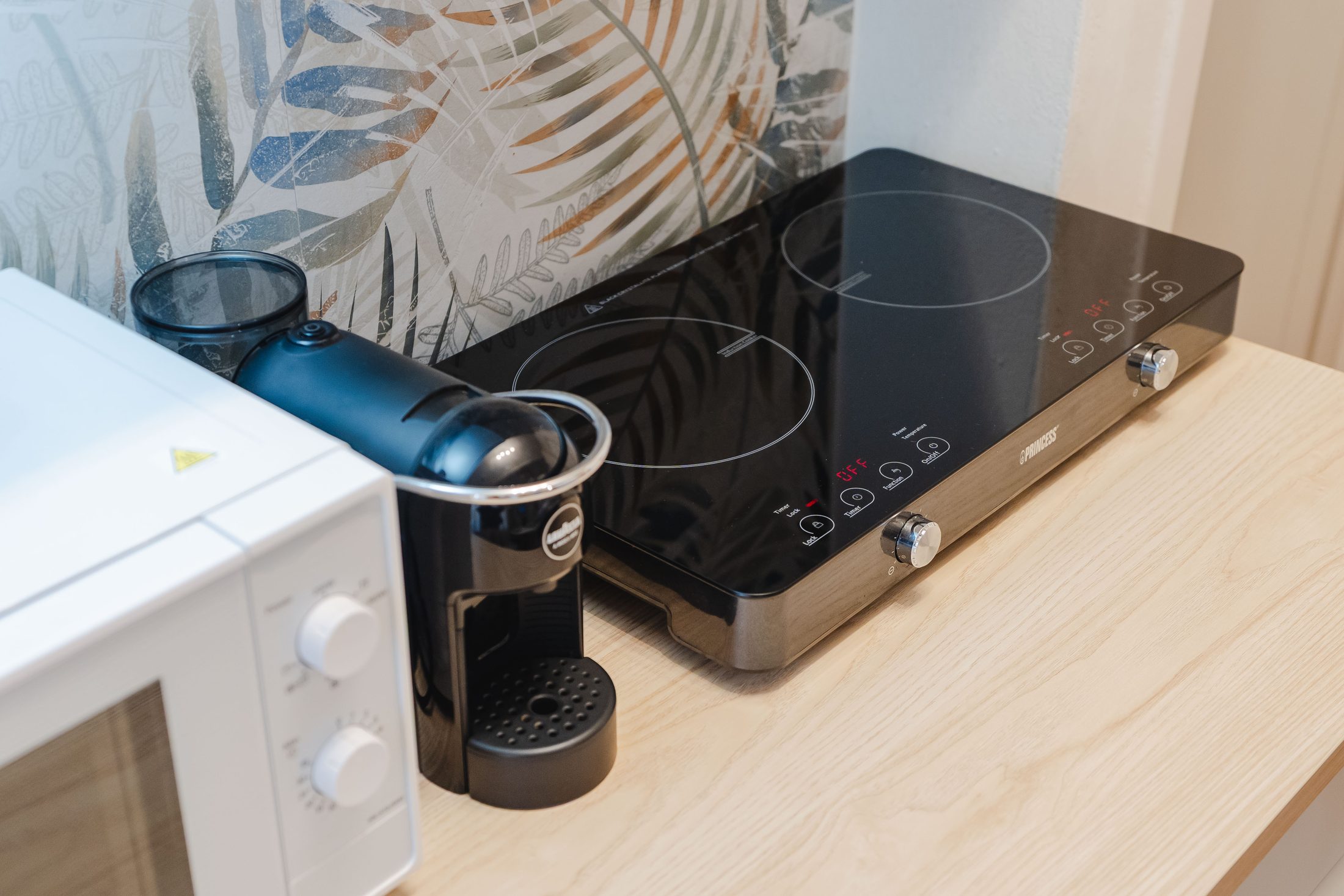 Angolo cucina con macchina del caffè a cialde, piano a induzione e microonde