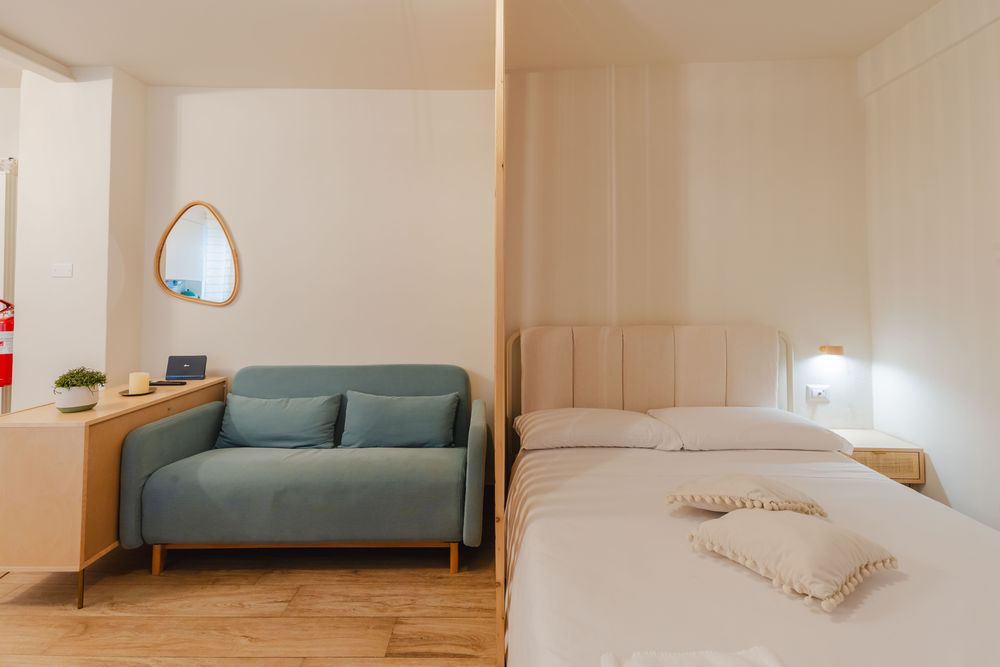 Divano letto azzurro accanto al letto matrimoniale
