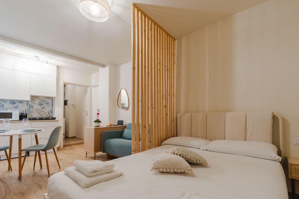 Letto matrimoniale con testiera imbottita e, sullo sfondo, la zona cucina