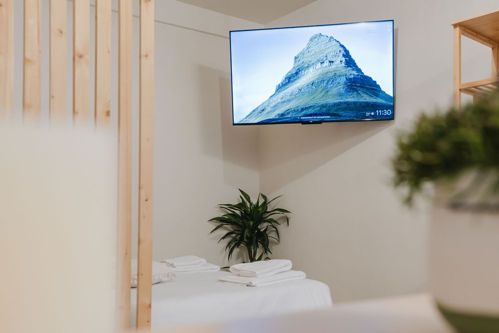 Televisione a parete e letto con asciugamani piegati